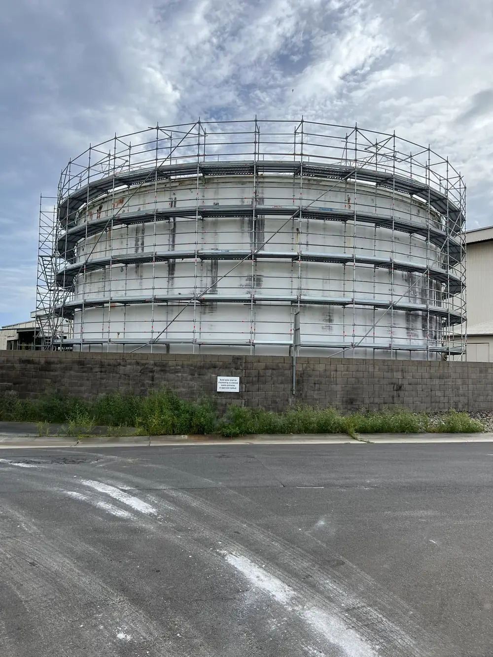 Scaffolding wrapped around a large cylindrical industrial tank