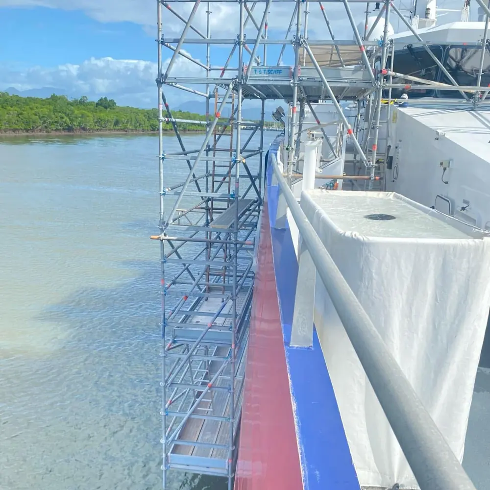Scaffolding erected alongside a vessel beside calm water