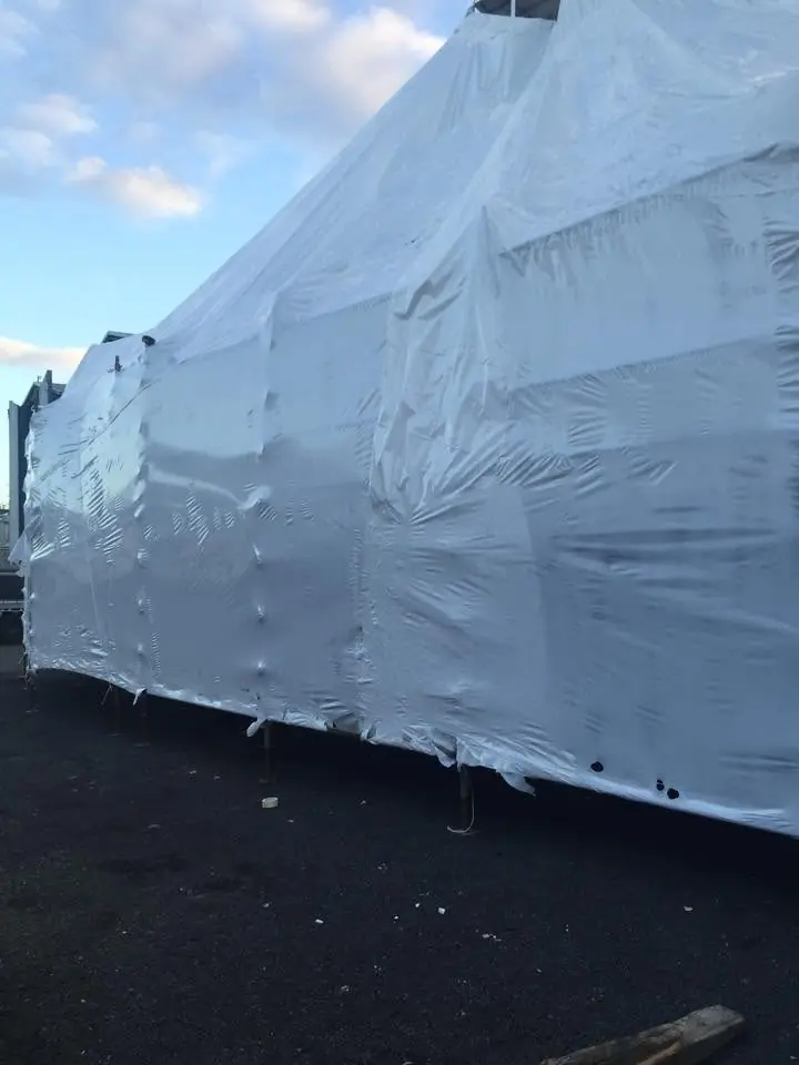 Large structure enclosed in white shrink wrap under a blue sky