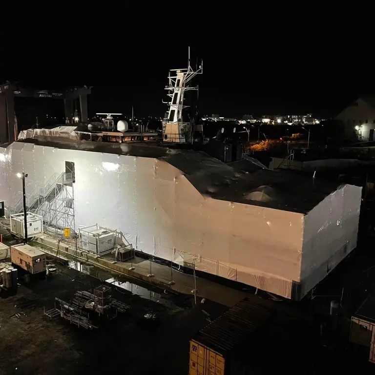 Large vessel enclosed in white protective wrapping at night