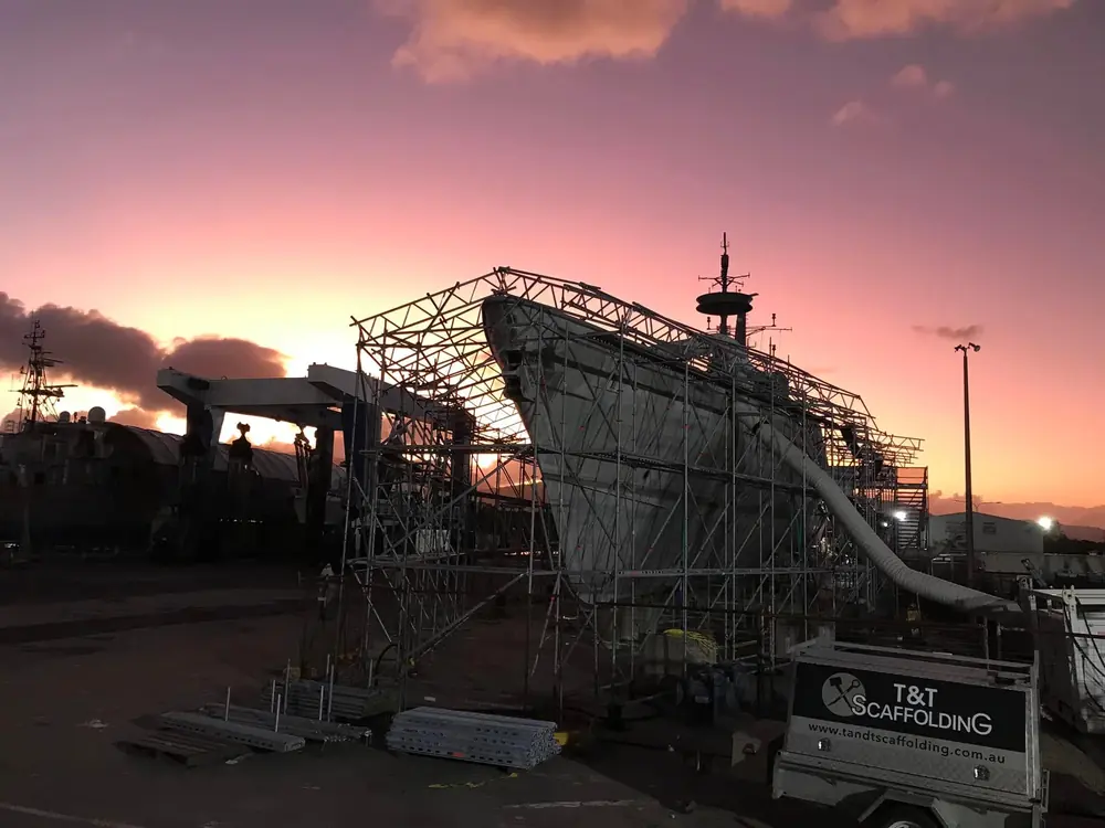 Roofed scaffold enclosure surrounding a vessel at sunset