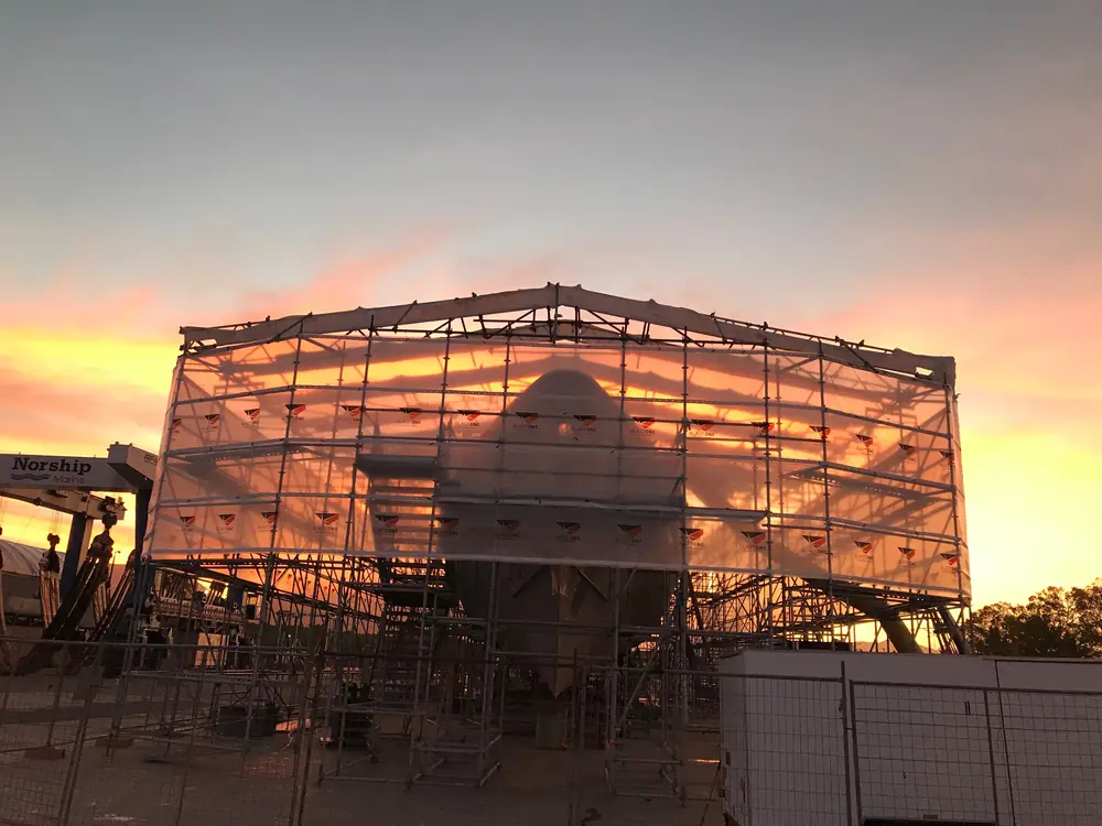 Temporary roof and wrapped scaffold enclosure around a vessel at sunset