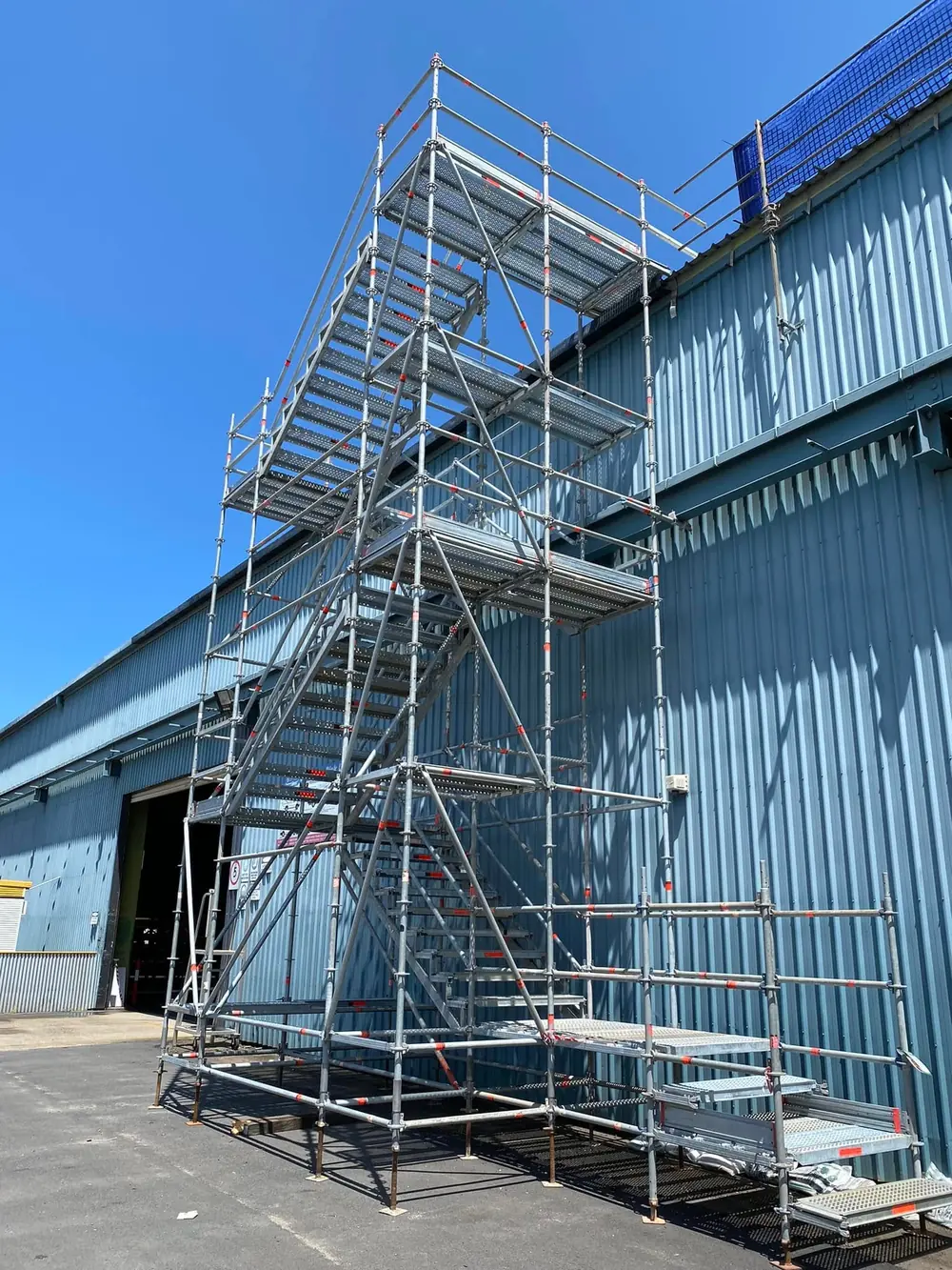 Modular scaffold stair system installed beside an industrial building