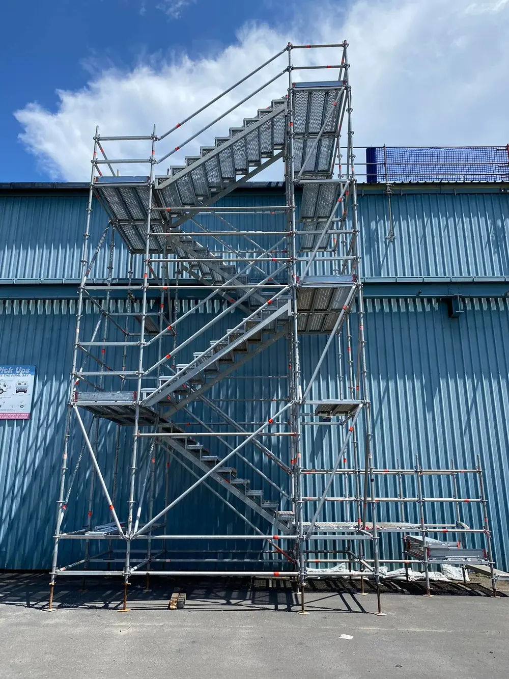 Modular scaffold stair tower beside an industrial building