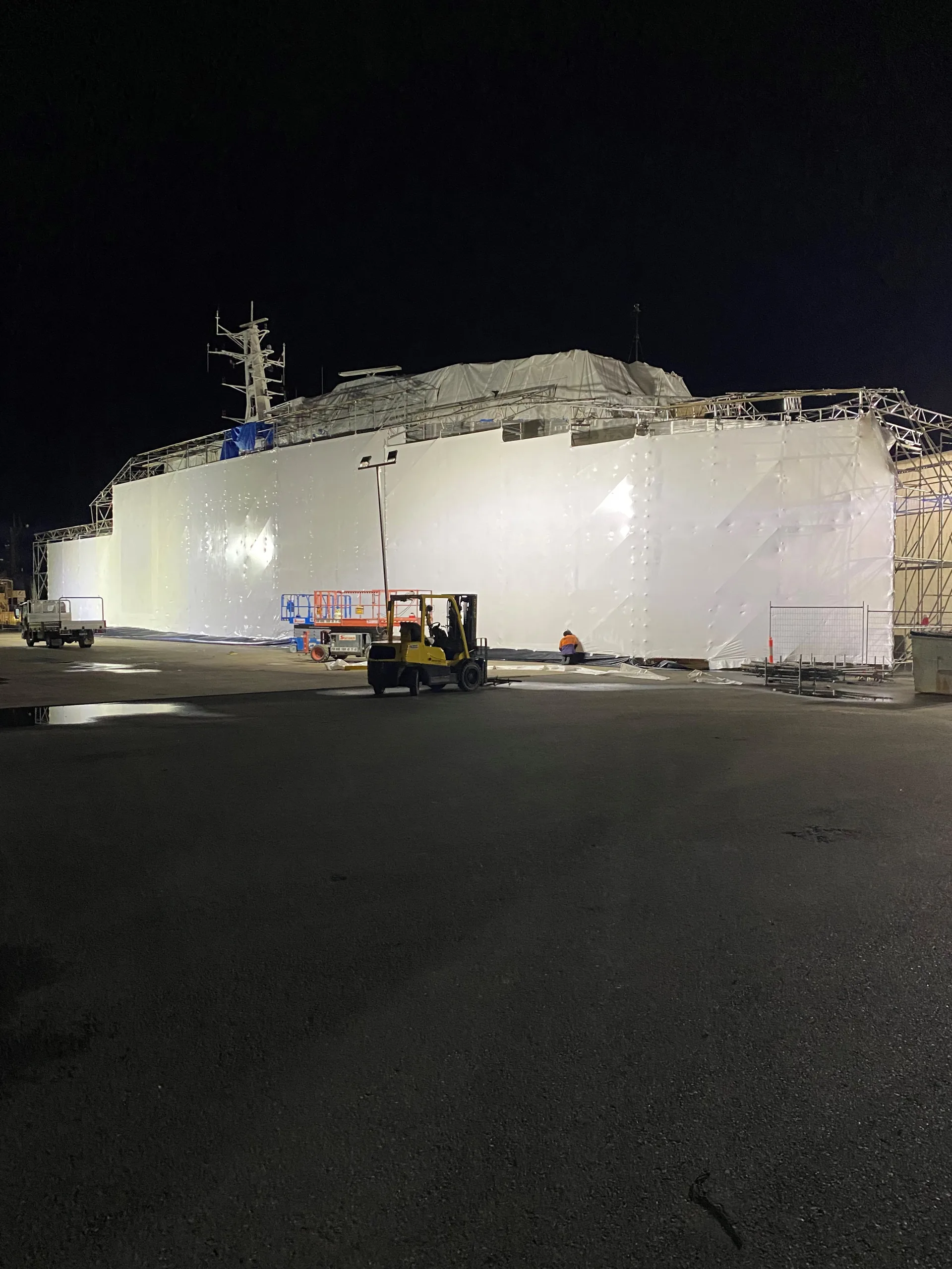 Large vessel enclosed in white shrink wrap during night works