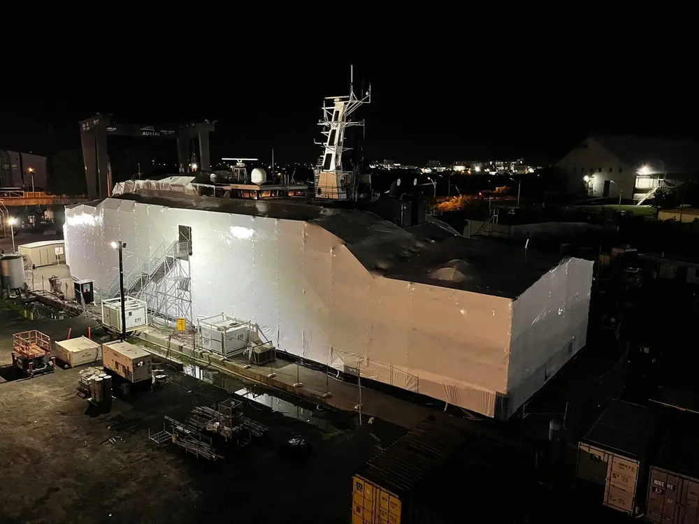 Large vessel enclosed in white shrink wrap during night works